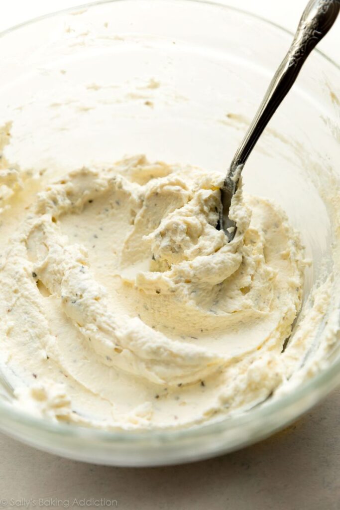 Creamy homemade frosting in a glass bowl with a spoon. Ideal for cakes and desserts.