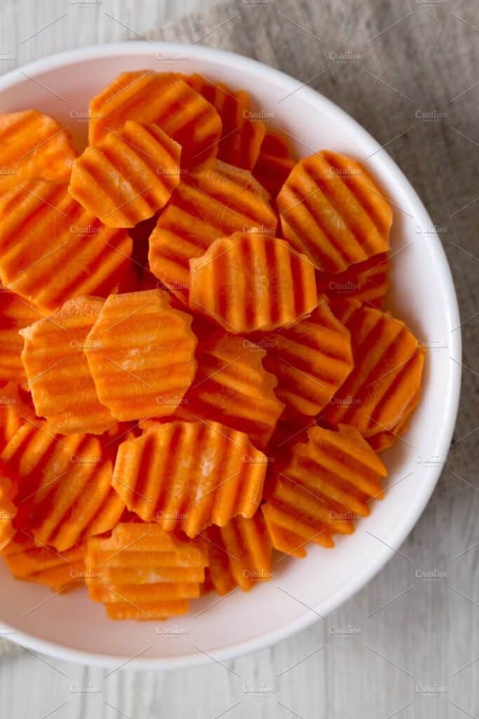 Crinkle-cut carrot slices in a white bowl, perfect for a healthy snack or salad topping.