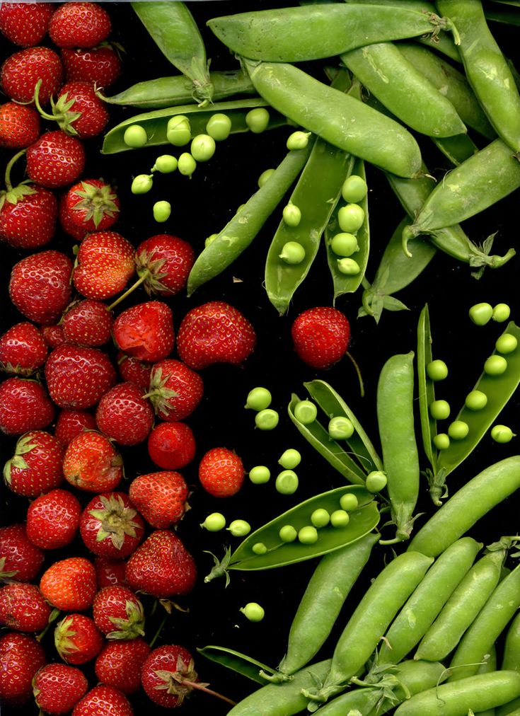 Fresh strawberries and green peas on a black background, showcasing vibrant colors and natural textures.