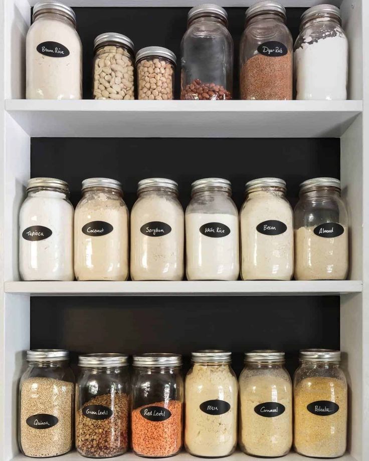 Labeled jars of pantry staples like rice, lentils, and flours neatly arranged on shelves for organized storage.