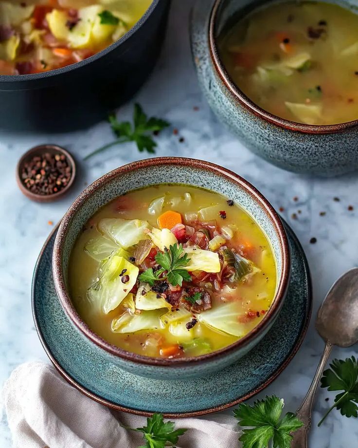 Hearty vegetable soup with cabbage, carrots, and fresh parsley in a rustic bowl on a marble table.