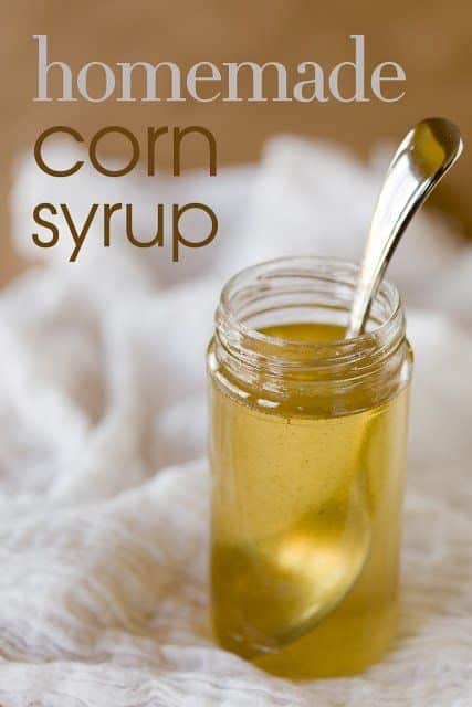 Jar of homemade corn syrup with a spoon on a white cloth background.