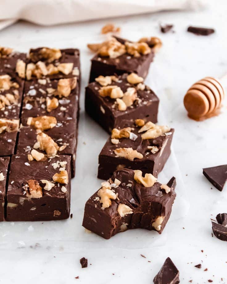 Chocolate fudge pieces with walnuts on a marble surface. Indulgent dessert treat.