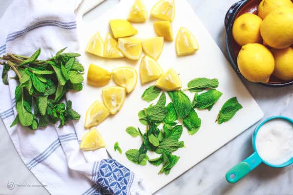 Fresh lemons and mint on a cutting board, ready for cooking or a refreshing drink.