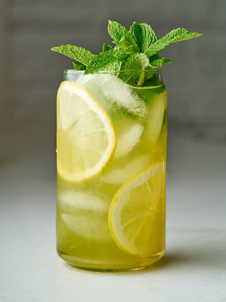 Refreshing iced mint lemonade with lemon slices and mint garnish in a tall glass. Perfect summer drink.