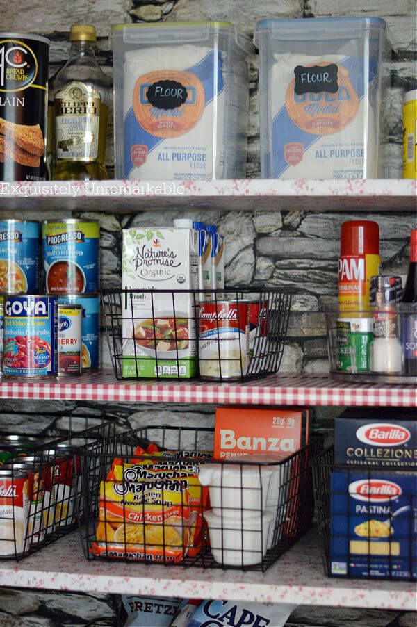 Organized pantry shelves with various food items, canned goods, and labeled flour containers.
