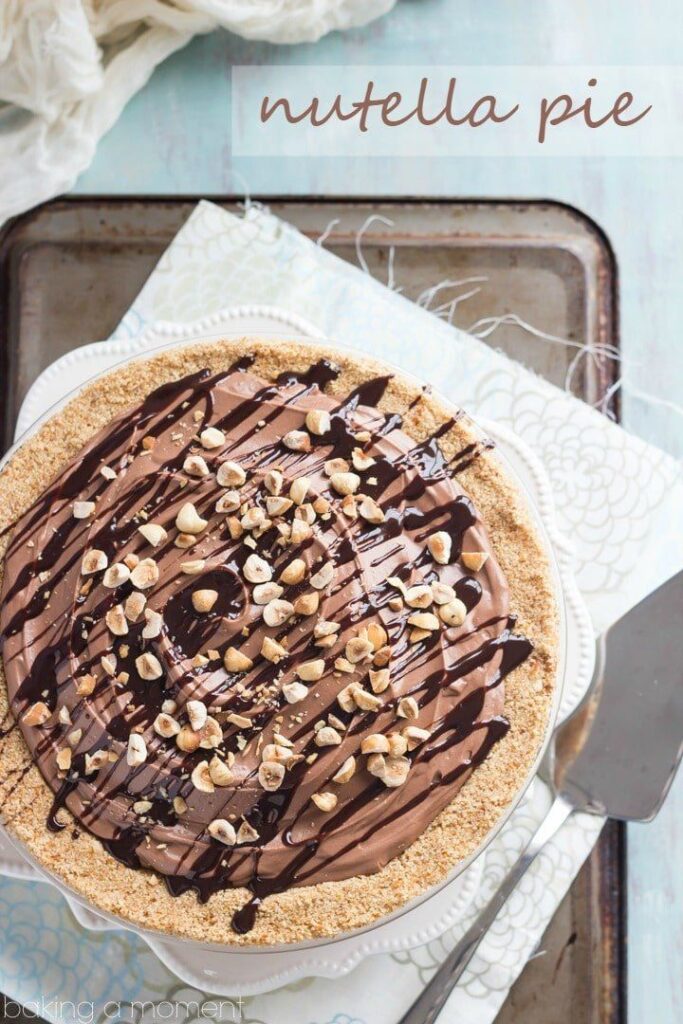 Delicious Nutella pie topped with nuts and drizzled chocolate on a baking tray, perfect dessert for chocolate lovers.