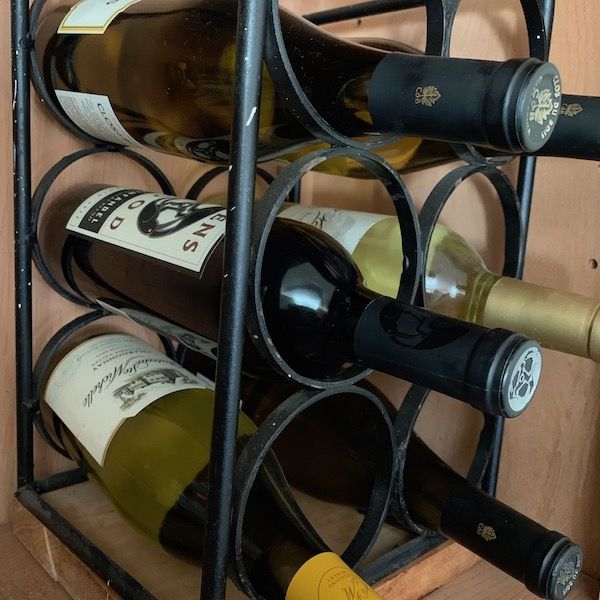 Wine rack with assorted bottles, neatly arranged in a stylish metal holder, placed against a wooden background.
