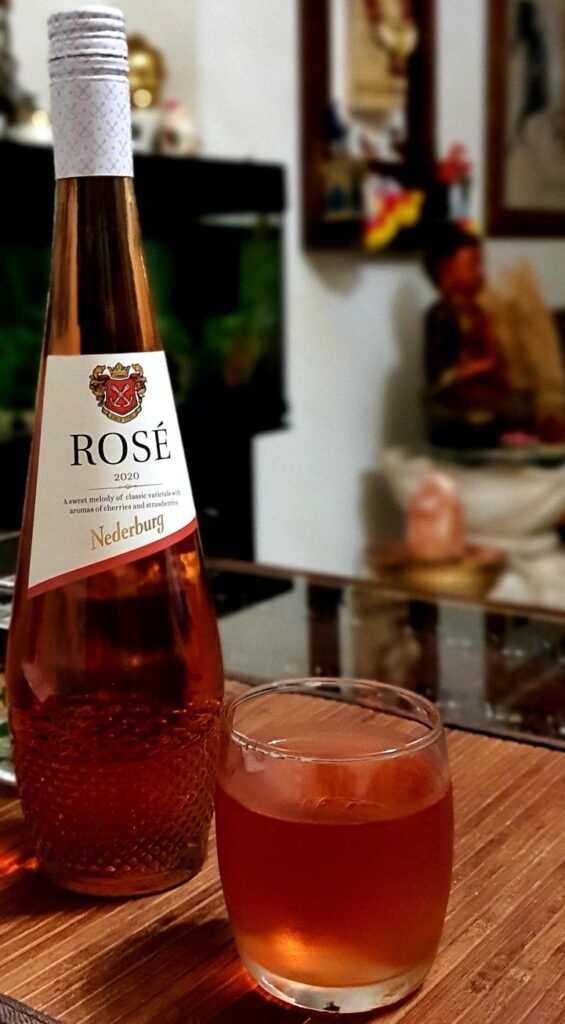 Rosé wine bottle and glass on table, ambient background, close-up view.
