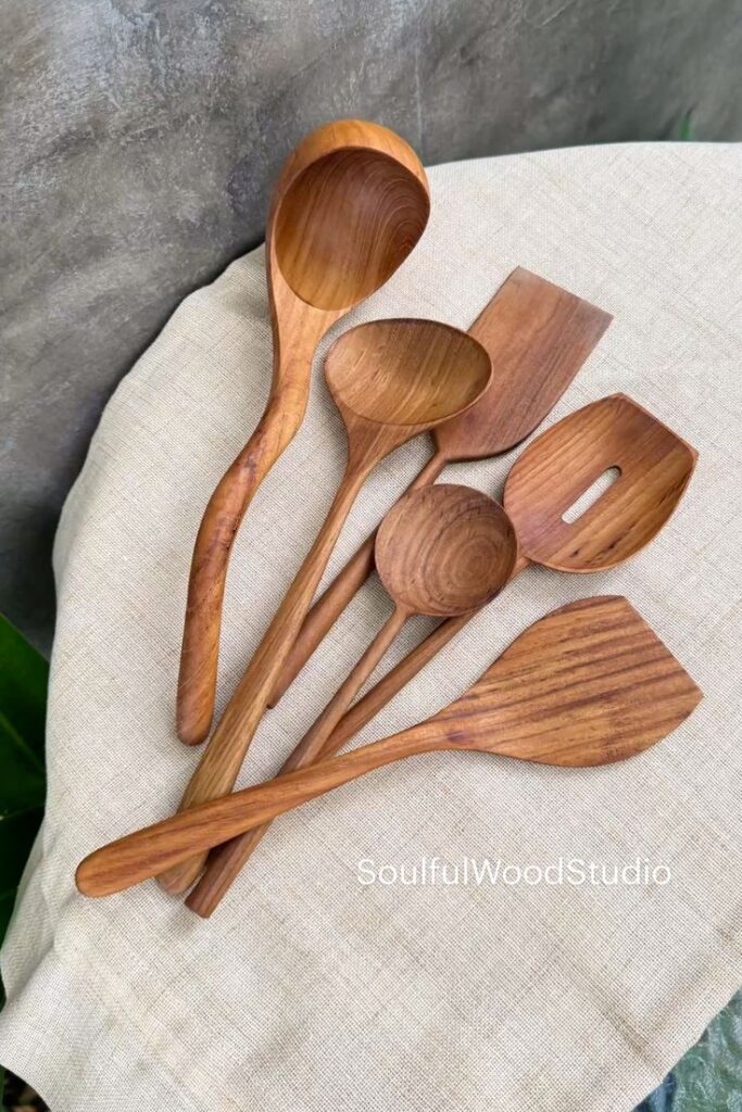 Handcrafted wooden kitchen utensils on beige fabric, featuring spoons and spatulas for cooking enthusiasts.