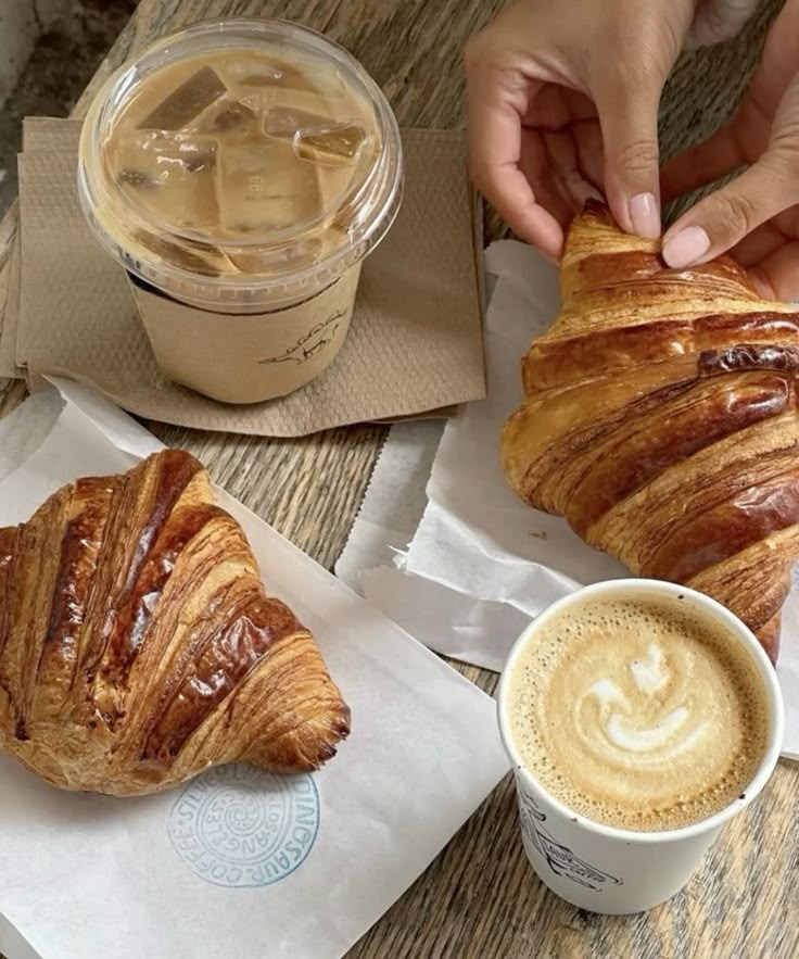 Fresh croissants with iced coffee and latte on a wooden table, perfect breakfast scene.