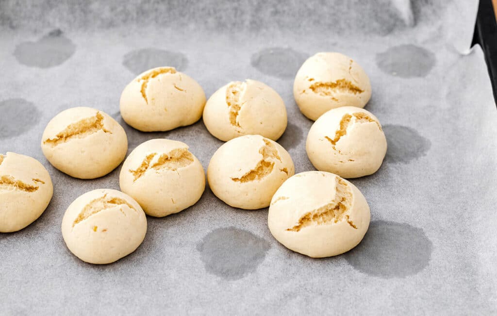Ten freshly baked, golden brown bread rolls on a baking sheet, ready to enjoy.