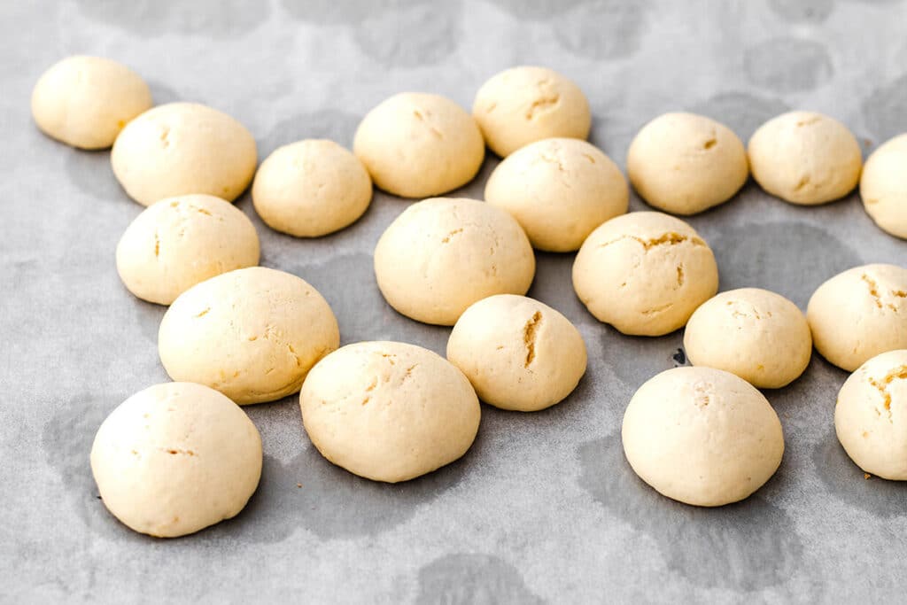 Baked cheese bread rolls on parchment paper, fresh from the oven. Perfect for a homemade snack.