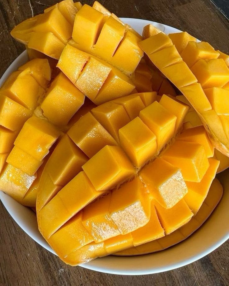 Bowl of ripe, sliced mangoes with juicy yellow flesh, arranged beautifully for a delicious tropical fruit snack.