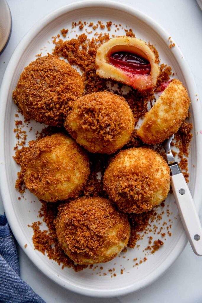 Delicious sugar-coated dumplings with a sweet plum filling on a white plate.