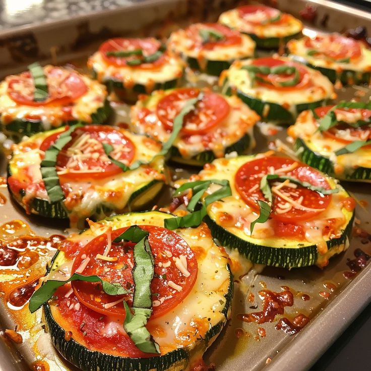 Zucchini pizza bites topped with tomato, cheese, and basil on a baking sheet, healthy and delicious snack.