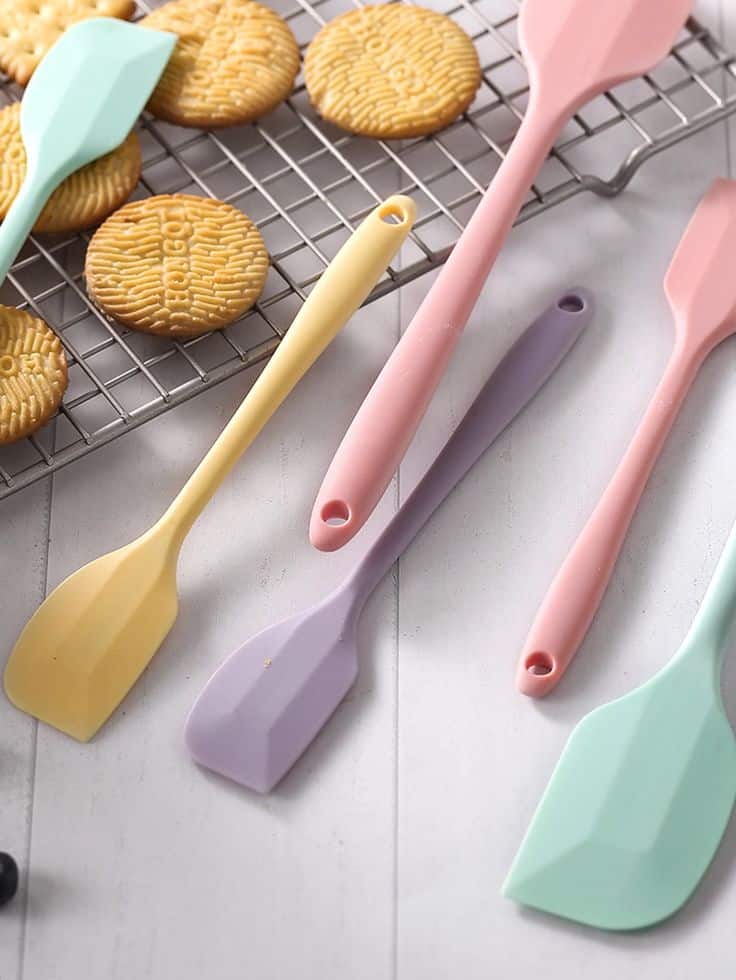 Colorful silicone spatulas and cookies on cooling rack on a kitchen countertop. Perfect tools for baking enthusiasts.