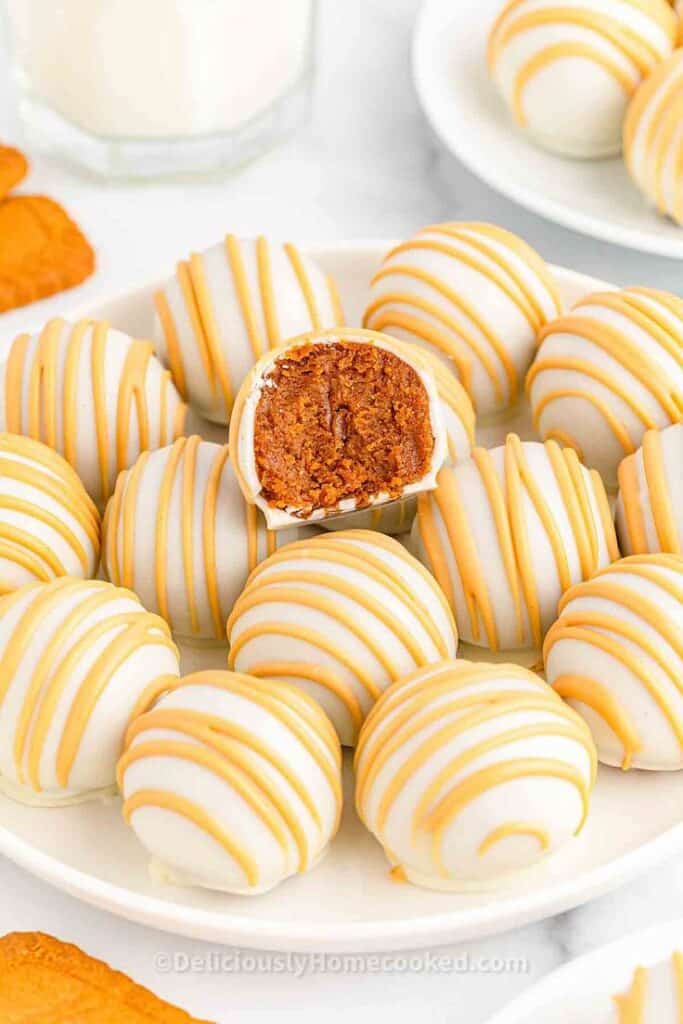 White chocolate truffles with orange drizzle on a plate, one is cut open, showcasing a rich brown filling.
