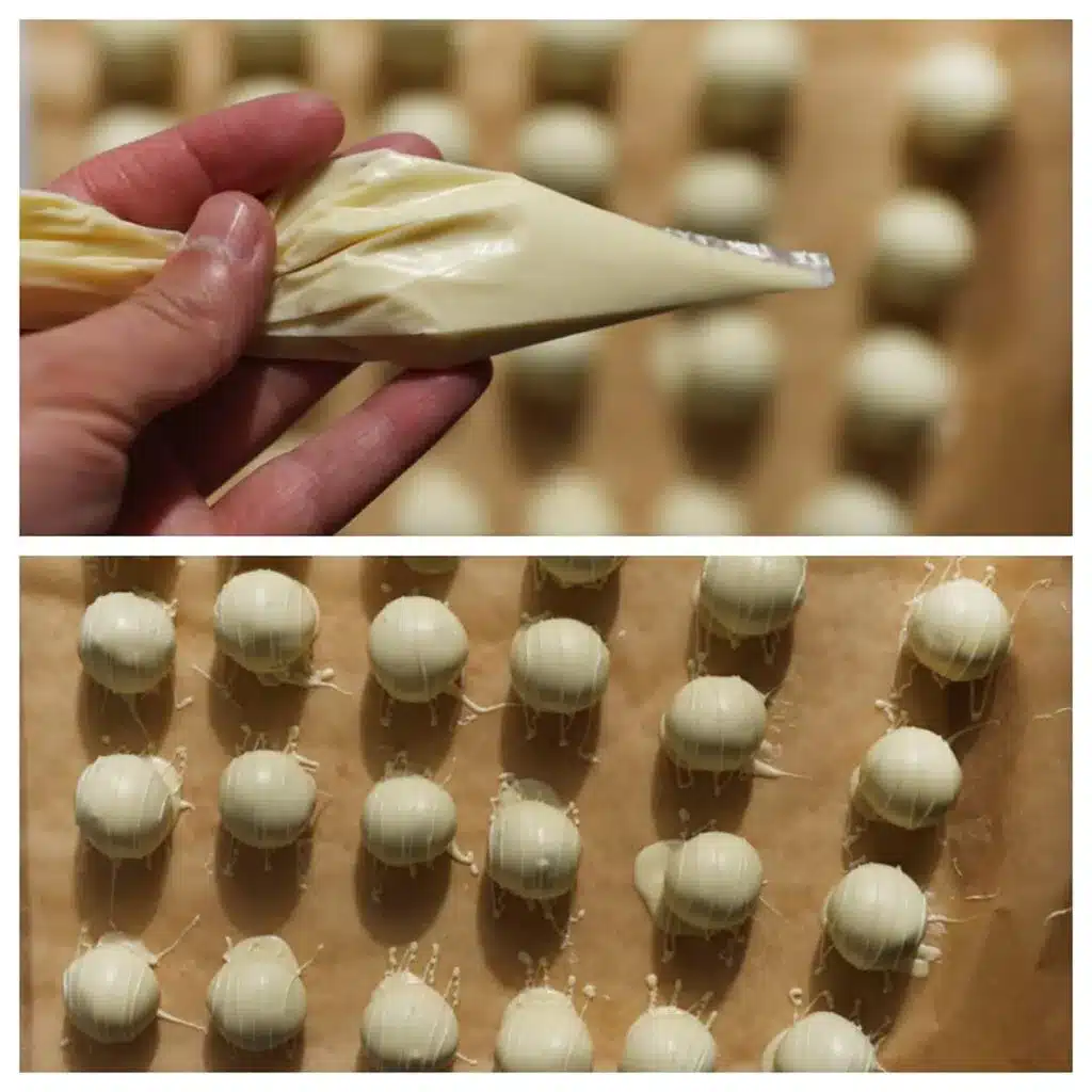 Hand piping white chocolate drizzle onto homemade truffles set on parchment paper.