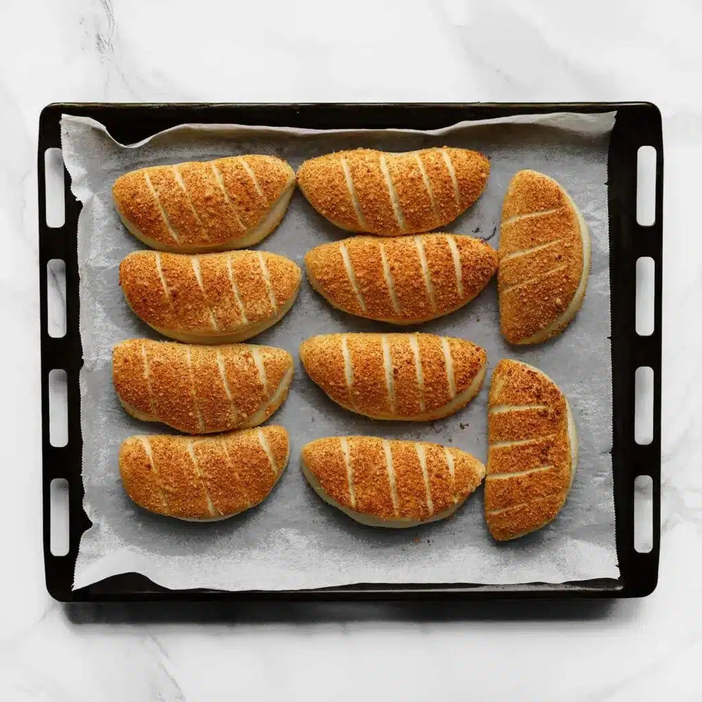 Freshly baked golden buns on a baking tray lined with parchment paper, ready to serve.
