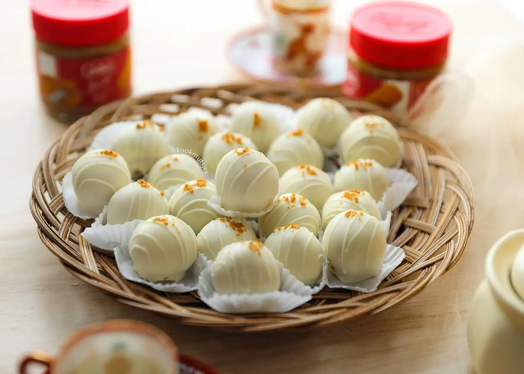 White chocolate truffles on a wicker plate, garnished with golden sprinkles. Ideal for festive and elegant occasions.