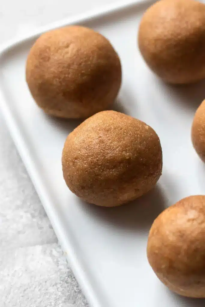 Close-up of round, brown cookies on a white tray, highlighting texture and freshness, perfect for dessert lovers.