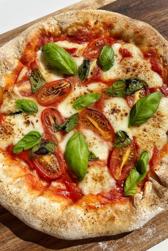 30-Minute Homemade Stuffed Crust Pizza - Myriad Recipes - Master the Art of Homemade Pizza with Fun, Simple Steps | Homemade Margherita pizza topped with fresh basil, cherry tomatoes, and melted mozzarella on a rustic wooden board.