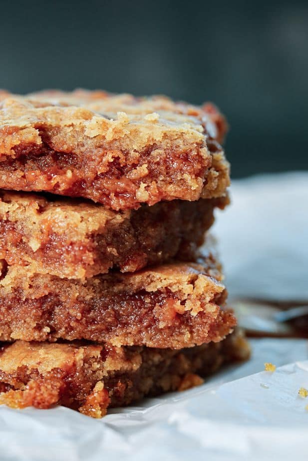 Stack of gooey, homemade blondies with a rich, golden crust on parchment paper. Perfect dessert or sweet treat.