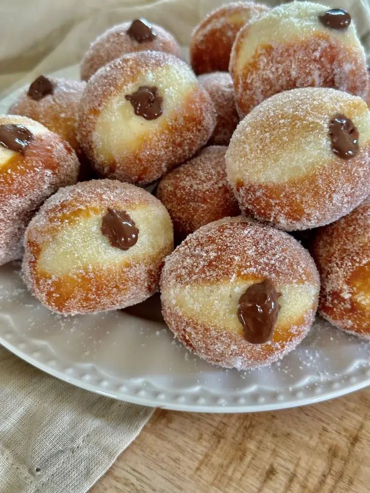 Plate of sugar-dusted donuts filled with creamy chocolate, perfect for a sweet treat or dessert indulgence.