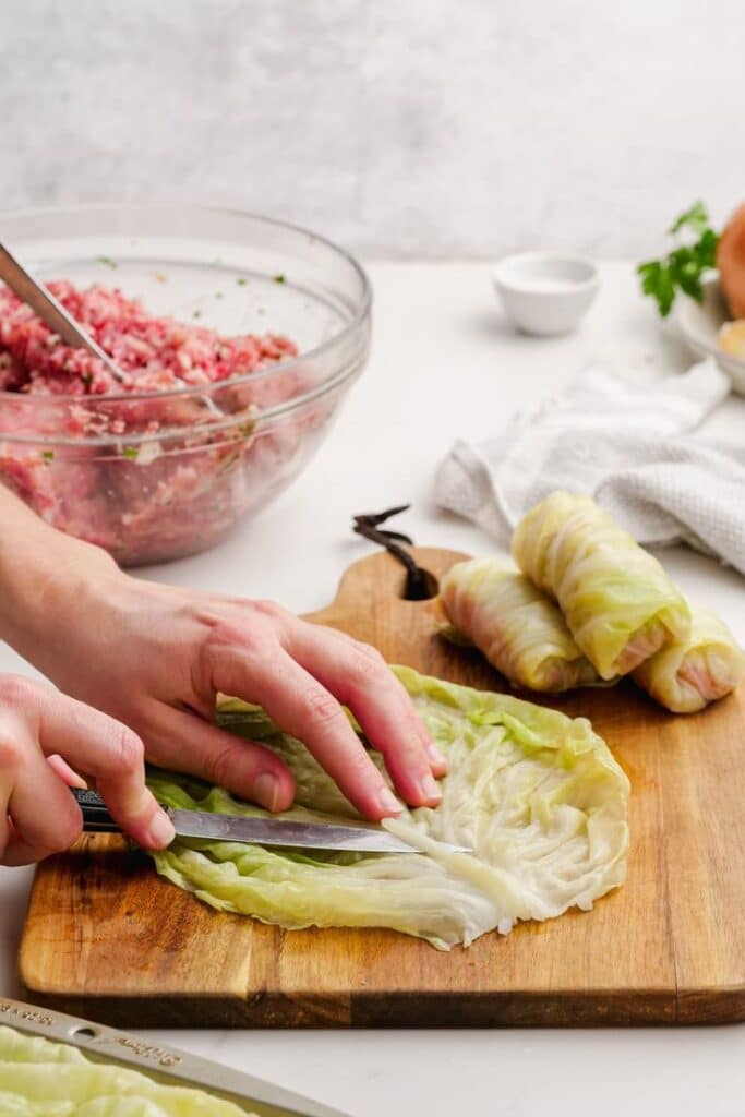 Preparing cabbage rolls with meat filling on a wooden board in the kitchen.