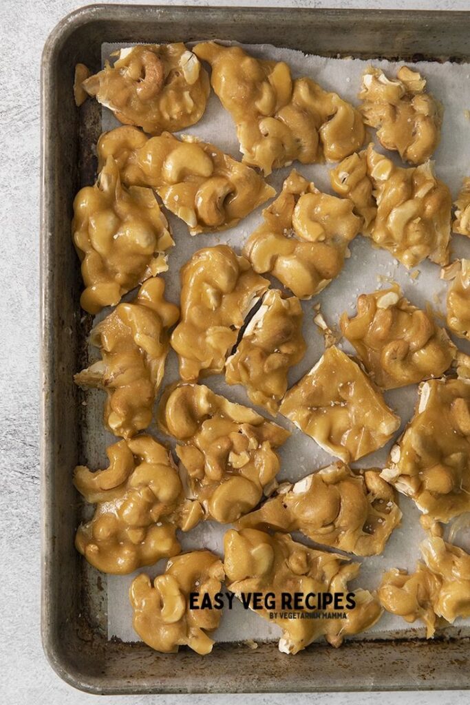Homemade cashew brittle on a baking tray lined with parchment paper, showcasing a delicious golden color.