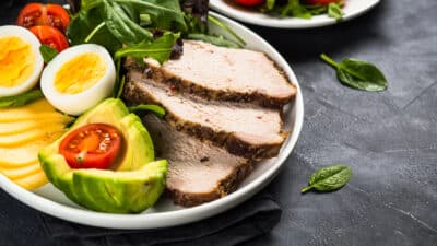 Keto-friendly meal with turkey, avocado, egg, cheese, and salad greens on a plate for a healthy diet option.