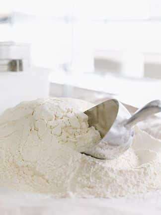 Flour power_ - Master the Art of Homemade Pizza with Fun, Simple Steps | Pile of white flour with a metal scoop in a bright kitchen setting. Ideal for baking and cooking enthusiasts.