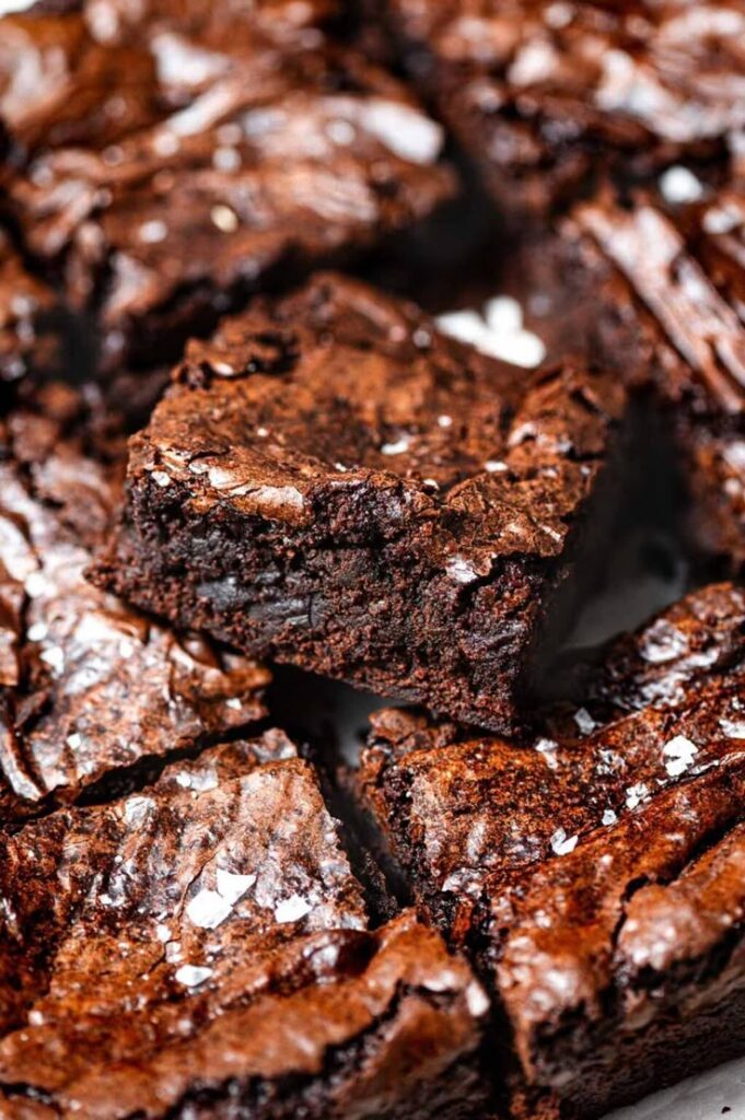 Rich, fudgy chocolate brownie with flaky sea salt topping, close-up texture shot.