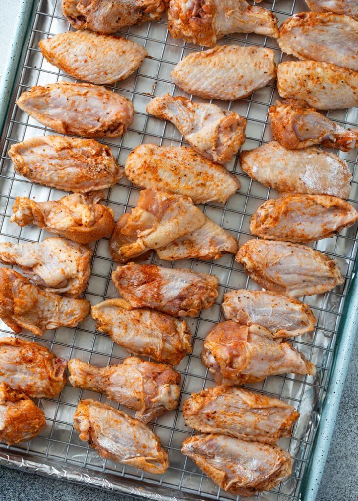 Seasoned chicken wings arranged on a baking sheet ready for cooking. Perfect for a delicious and easy meal prep.