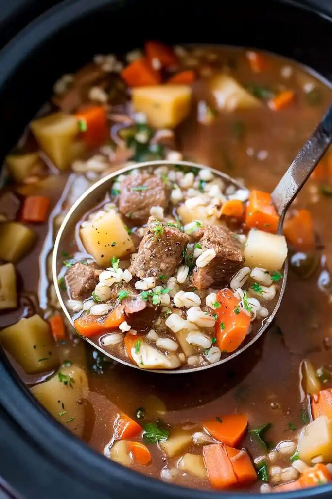 Hearty beef barley soup with carrots and potatoes in a ladle, perfect for a comforting, homemade meal.