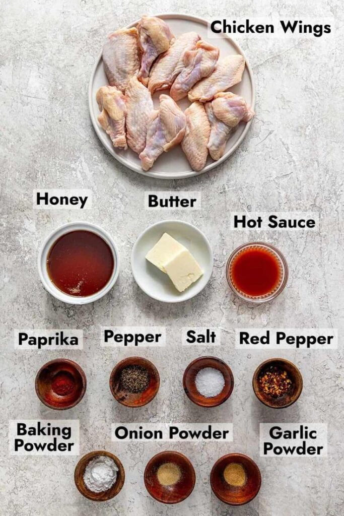 Ingredients for delicious chicken wings: raw wings, honey, butter, hot sauce, spices, baking powder, and garlic.