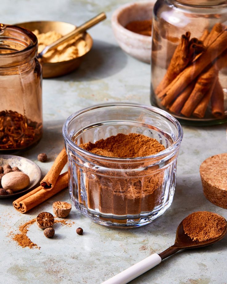 Assorted spices with cinnamon sticks and ground powder in jars, highlighting warm autumn flavors and culinary ingredients.