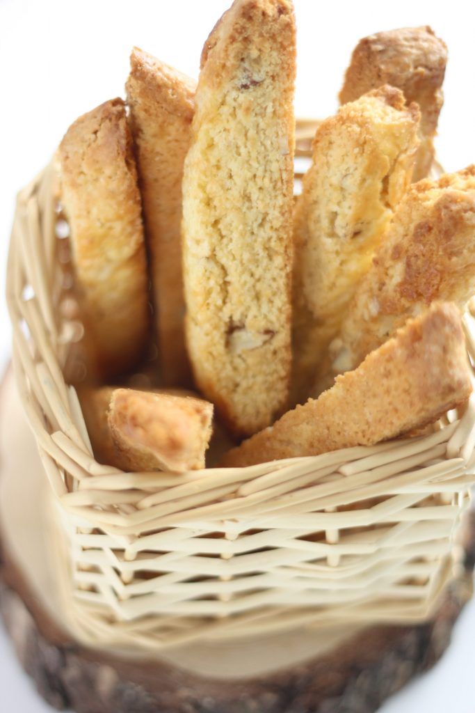 Basket of homemade biscotti on a wooden board, perfect for a crunchy snack or coffee companion.