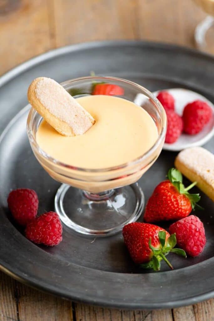 Creamy dessert with ladyfinger, fresh strawberries, and raspberries on a plate. Perfect sweet treat!
