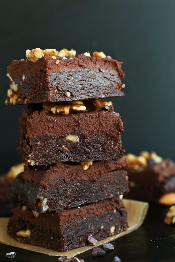 Stack of rich, fudgy brownies with walnuts on a wooden board. Perfect dessert for chocolate lovers.