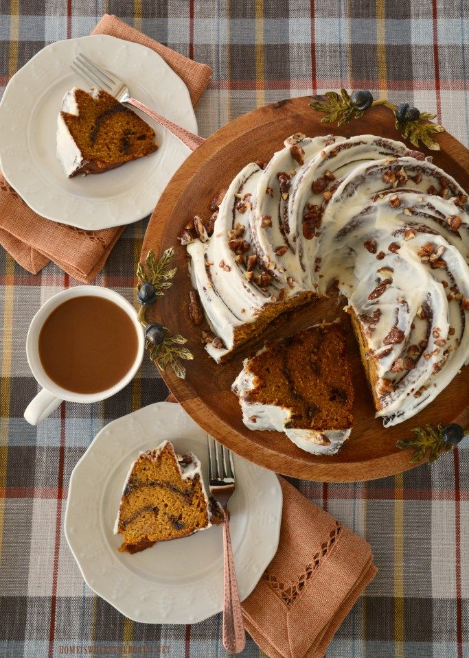 Pumpkin spice bundt cake with icing, pecans, coffee and slices on plates, on a plaid tablecloth, perfect fall dessert.