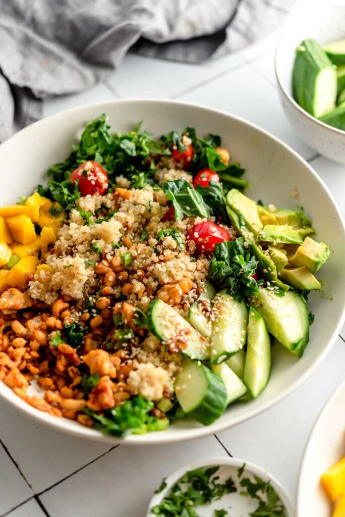 Healthy quinoa salad bowl with avocado, cucumber, cherry tomatoes, and greens. Vegan meal option.