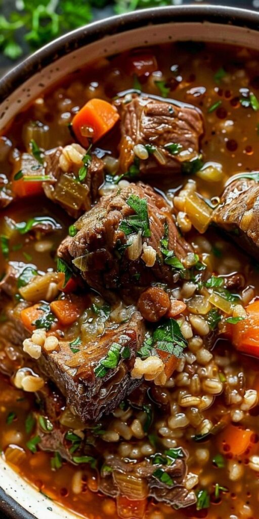 Hearty beef barley soup with vegetables in a bowl, garnished with fresh herbs. Perfect for a cozy meal.
