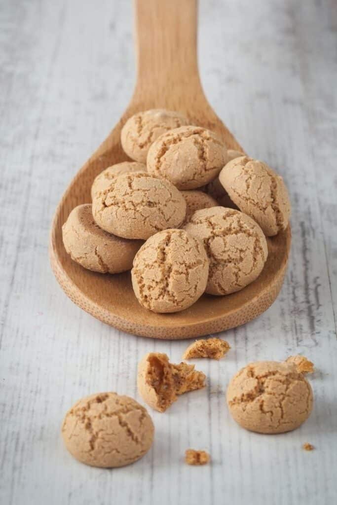 Wooden spoon with crunchy amaretti cookies on rustic table.