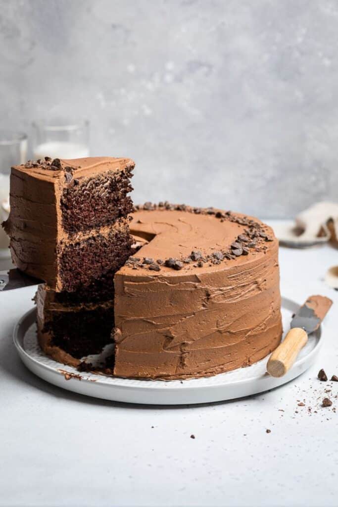 Delicious chocolate layer cake with rich frosting, topped with chocolate chips, and a slice being served.