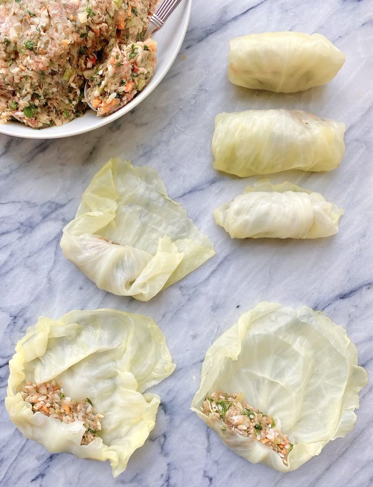 Preparing cabbage rolls with a savory filling on a marble countertop.