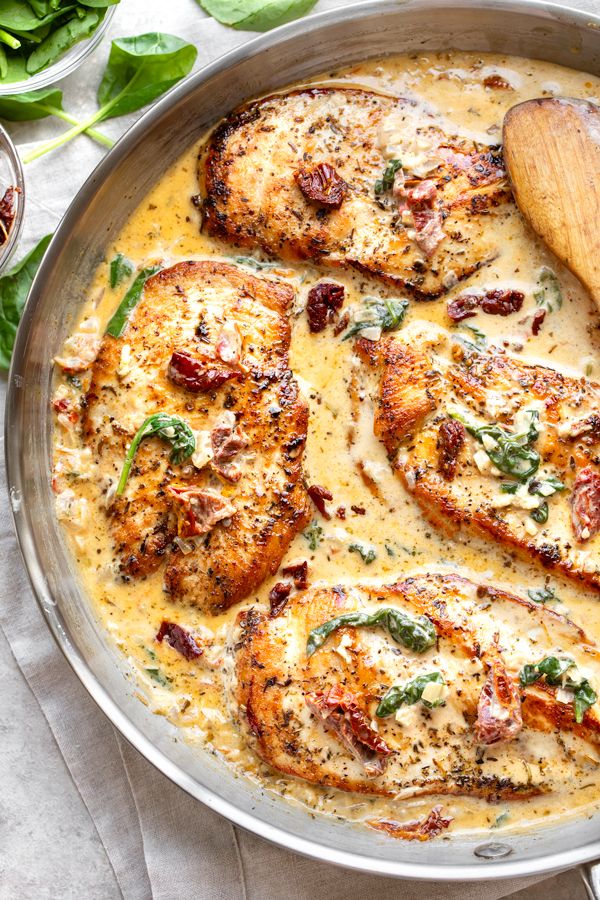 Creamy Tuscan chicken breasts with spinach and sun-dried tomatoes in a skillet, cooked in a rich, savory sauce.