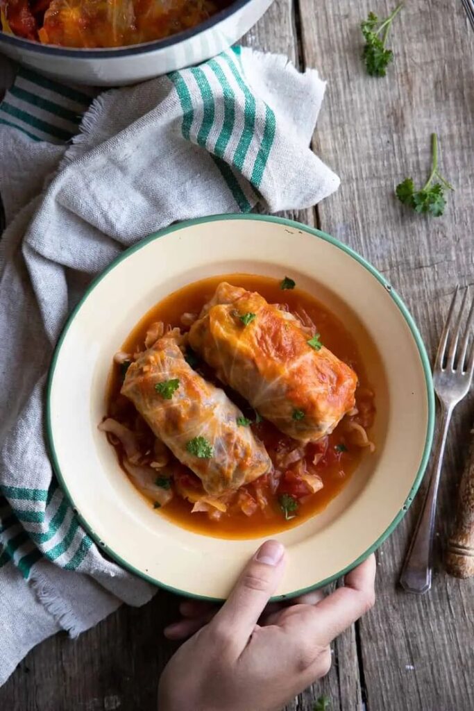 Delicious stuffed cabbage rolls served on a wooden table with vintage napkin and fork.