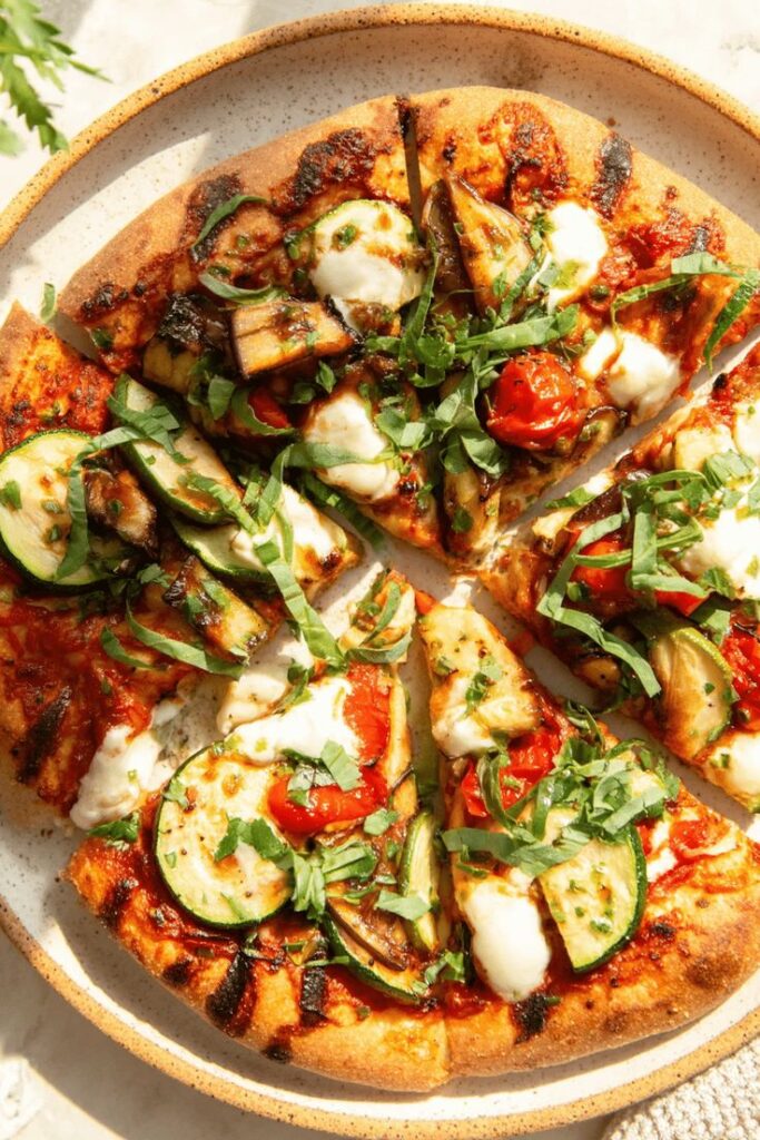 Veggie Pizza - Master the Art of Homemade Pizza with Fun, Simple Steps | Vegetable pizza topped with zucchini, tomatoes, mozzarella, and fresh herbs on a speckled plate.